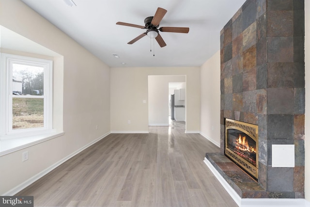 unfurnished living room featuring a tile fireplace, wood-type flooring, and ceiling fan