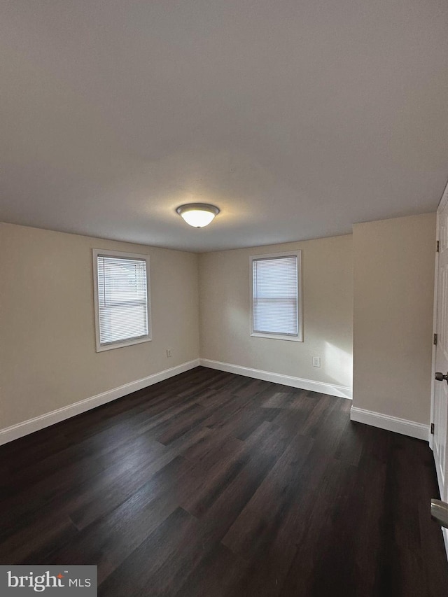 empty room with a wealth of natural light and dark hardwood / wood-style flooring