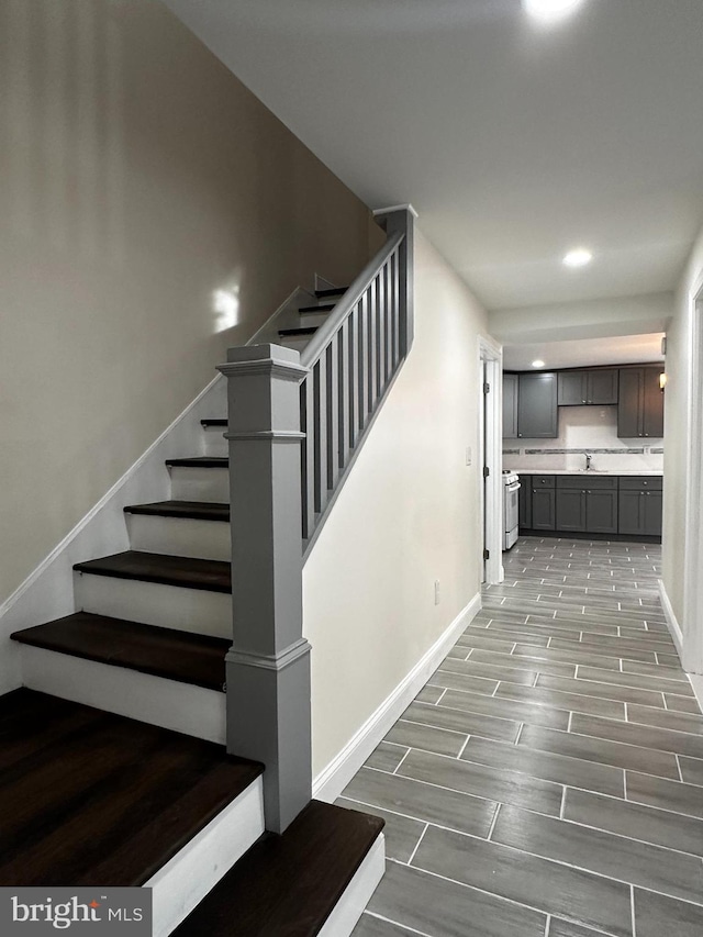 staircase with wood-type flooring and sink