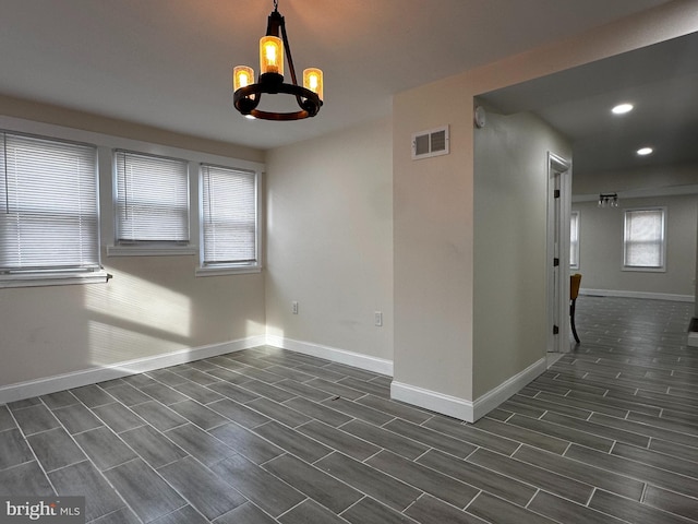 spare room featuring an inviting chandelier and dark hardwood / wood-style flooring