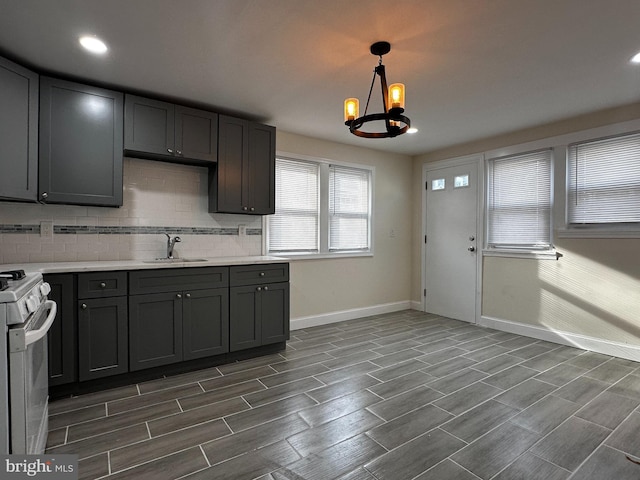 kitchen featuring sink, an inviting chandelier, decorative light fixtures, dark hardwood / wood-style flooring, and electric stove