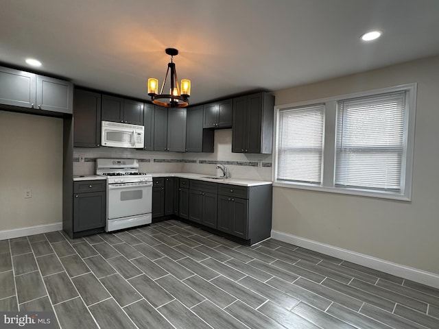 kitchen featuring sink, decorative light fixtures, white appliances, a notable chandelier, and dark hardwood / wood-style flooring