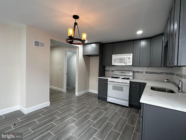 kitchen with hanging light fixtures, white appliances, an inviting chandelier, and gray cabinets