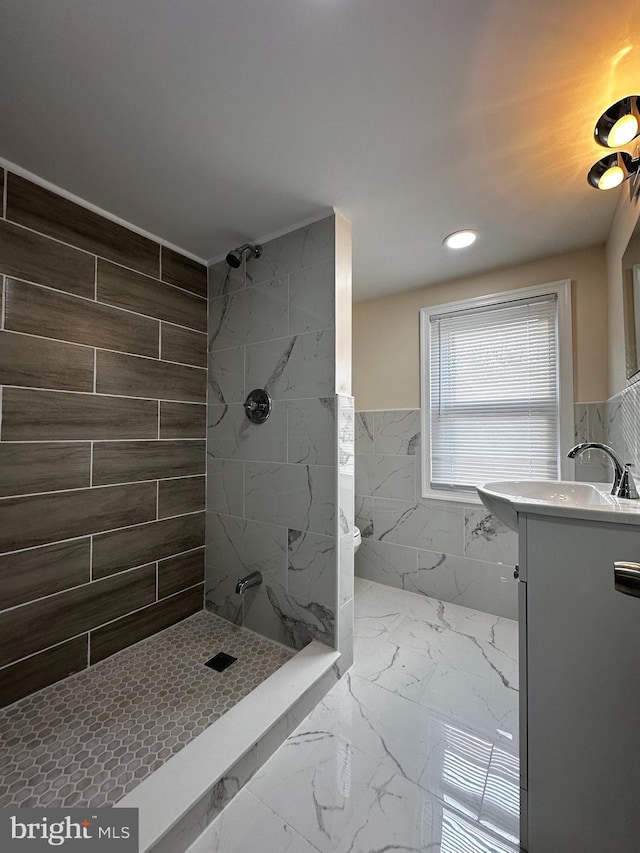 bathroom with tile walls, vanity, and a tile shower