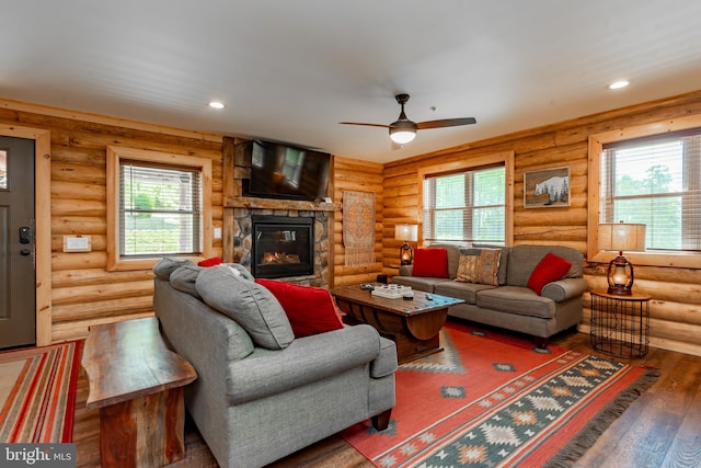 living room with rustic walls, dark hardwood / wood-style floors, a healthy amount of sunlight, and ceiling fan