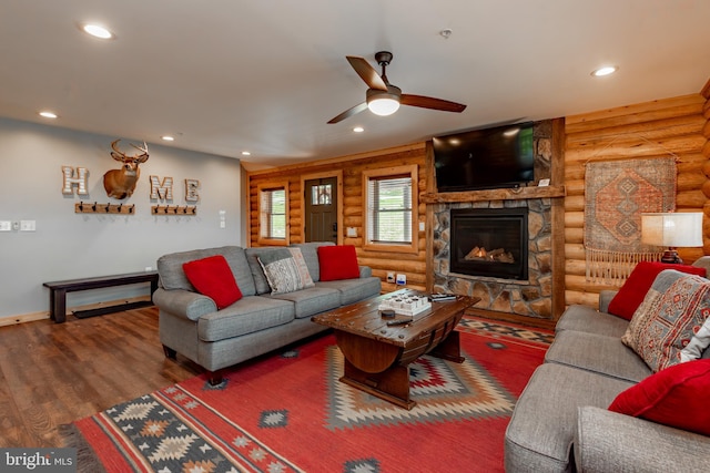 living room with log walls, a stone fireplace, dark hardwood / wood-style floors, and ceiling fan