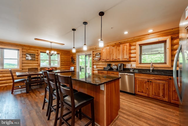 kitchen with appliances with stainless steel finishes, rustic walls, dark hardwood / wood-style floors, and plenty of natural light