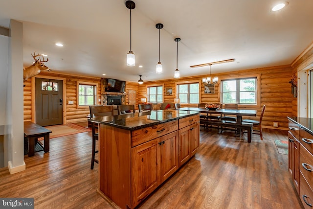 kitchen featuring dark wood-type flooring, log walls, decorative light fixtures, and a kitchen breakfast bar