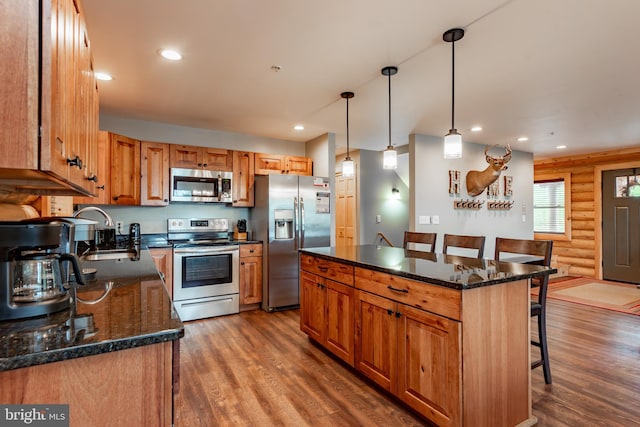 kitchen featuring hanging light fixtures, a center island, a kitchen bar, appliances with stainless steel finishes, and dark hardwood / wood-style flooring