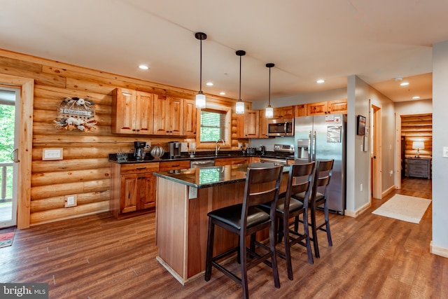 kitchen with stainless steel appliances, dark wood-type flooring, rustic walls, pendant lighting, and a center island