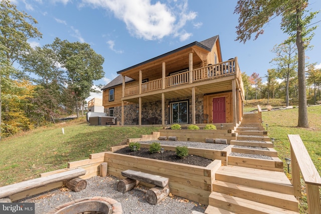 rear view of property featuring a lawn and a fire pit