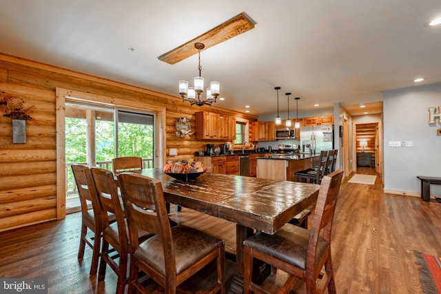 dining room with an inviting chandelier, dark wood-type flooring, and rustic walls