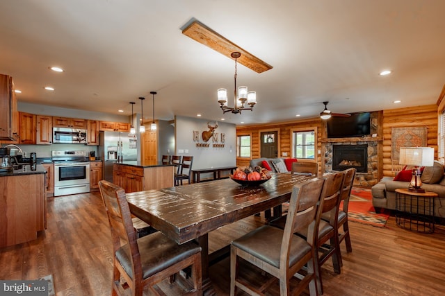 dining room with a fireplace, ceiling fan with notable chandelier, and dark hardwood / wood-style flooring