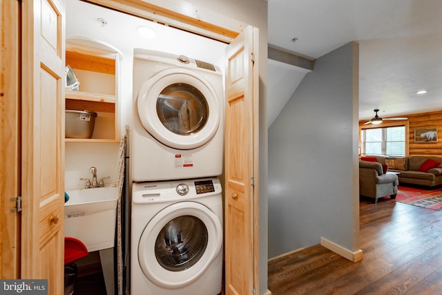 laundry area with stacked washing maching and dryer, sink, dark wood-type flooring, and ceiling fan