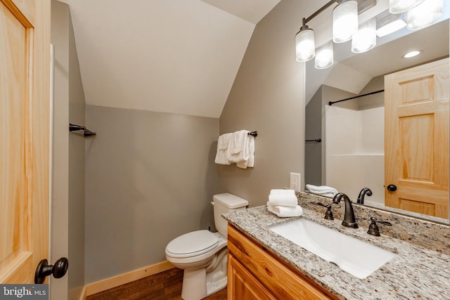 bathroom featuring vanity, hardwood / wood-style flooring, toilet, and vaulted ceiling