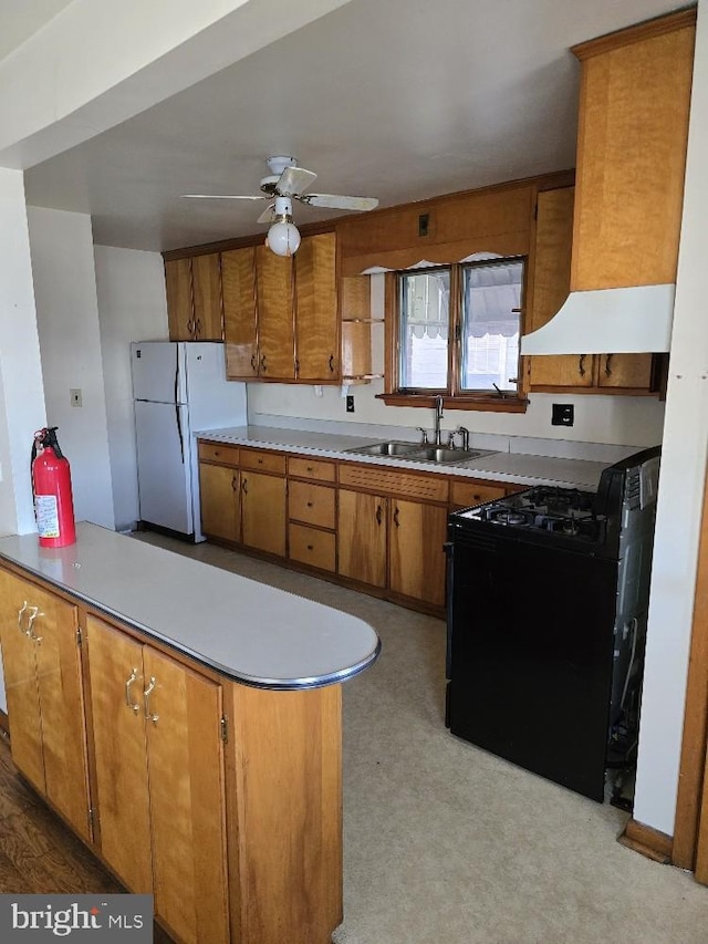 kitchen featuring black range with electric cooktop, kitchen peninsula, ceiling fan, white fridge, and sink