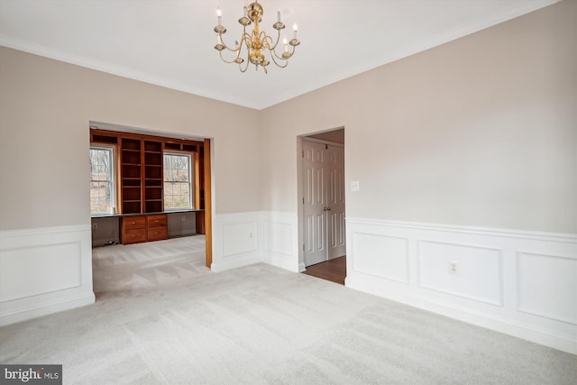 unfurnished room with carpet floors, ornamental molding, and a notable chandelier