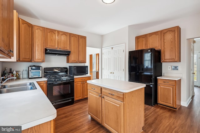 kitchen with black appliances, dark hardwood / wood-style floors, a kitchen island, and sink