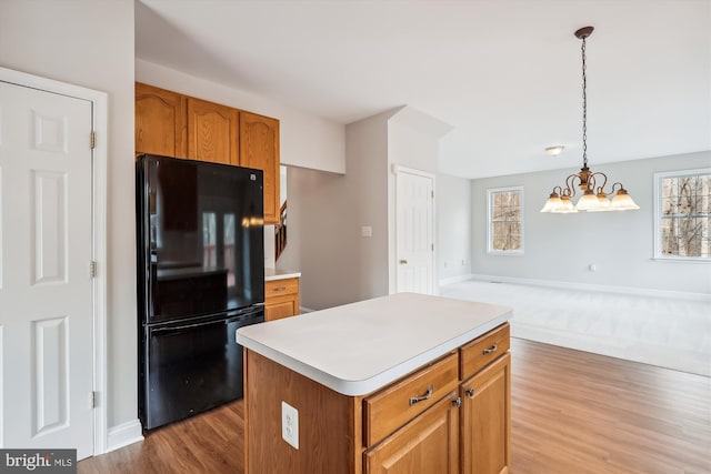 kitchen with plenty of natural light, black refrigerator, a kitchen island, and hanging light fixtures