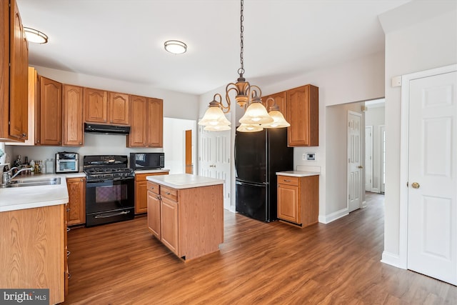 kitchen featuring dark hardwood / wood-style flooring, sink, black appliances, decorative light fixtures, and a center island