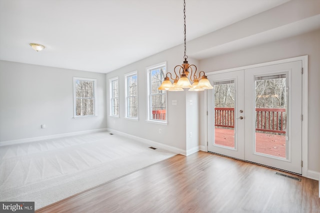 unfurnished dining area with hardwood / wood-style floors, a wealth of natural light, and a notable chandelier