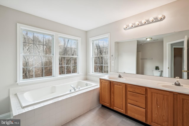 bathroom featuring tiled tub and vanity