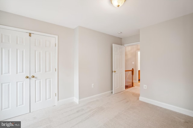 unfurnished bedroom featuring light carpet and a closet