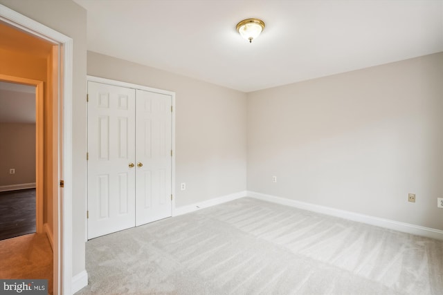 unfurnished bedroom with light carpet and a closet