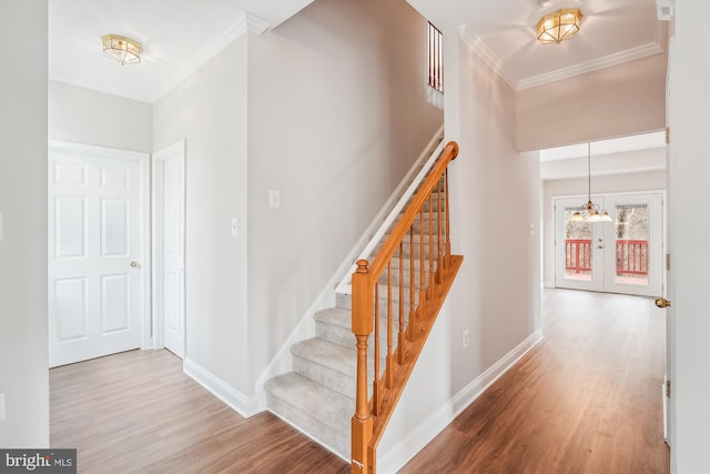 stairway with hardwood / wood-style floors, french doors, and crown molding