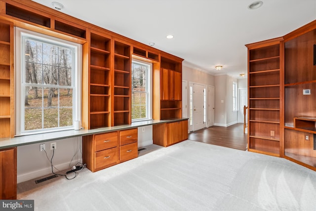 office area with light wood-type flooring, built in desk, and crown molding