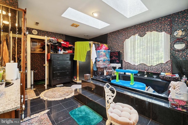 bathroom with a relaxing tiled tub, tile patterned floors, and a skylight