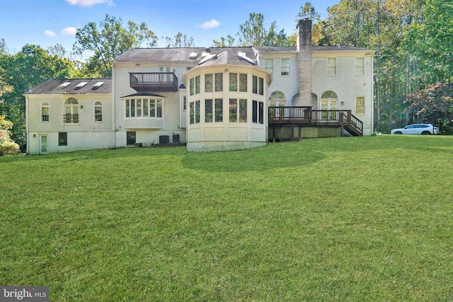 back of property with a deck and a lawn