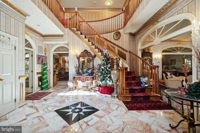 foyer with a towering ceiling and crown molding