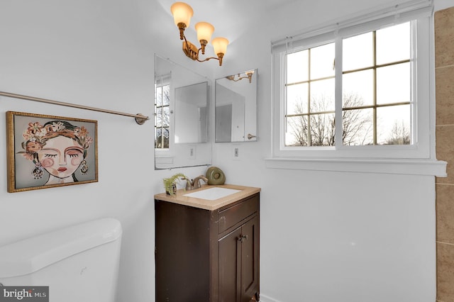 bathroom featuring toilet, vanity, tile walls, and an inviting chandelier