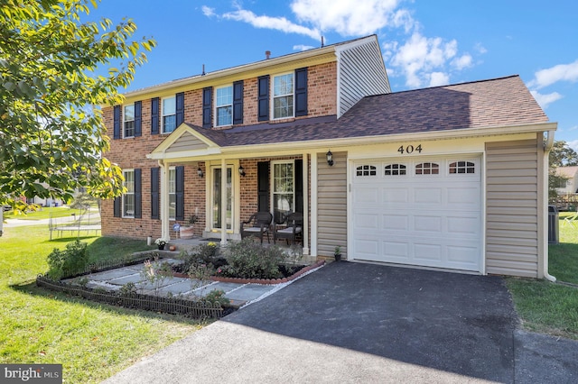 colonial house featuring a front yard, a porch, and a garage