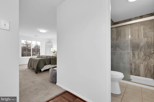 bathroom featuring tile patterned floors, toilet, and an enclosed shower