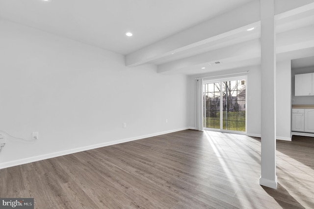 spare room with beam ceiling and wood-type flooring