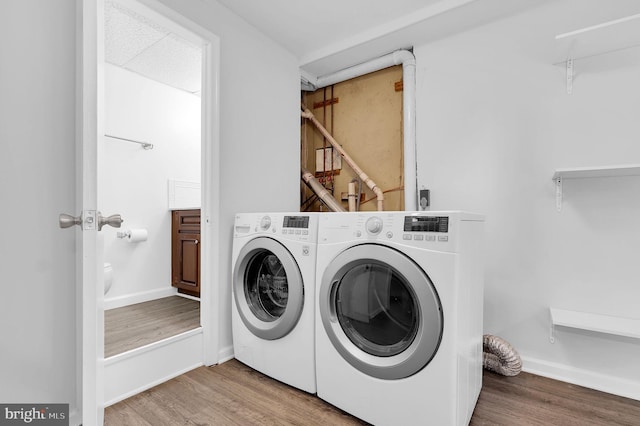 clothes washing area featuring hardwood / wood-style floors and washing machine and clothes dryer