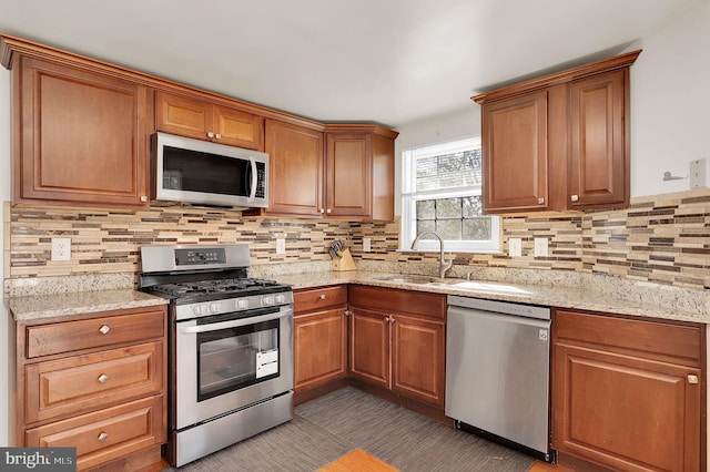 kitchen with tasteful backsplash, light stone counters, sink, and stainless steel appliances