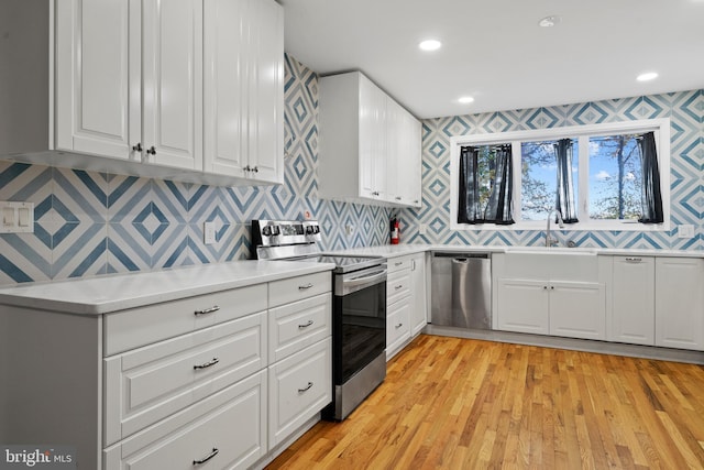 kitchen featuring sink, light hardwood / wood-style flooring, white cabinets, and appliances with stainless steel finishes