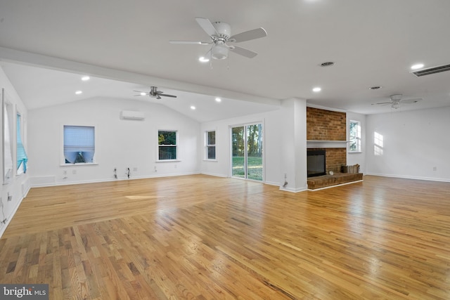 unfurnished living room with a wall mounted air conditioner, light hardwood / wood-style floors, a fireplace, and vaulted ceiling