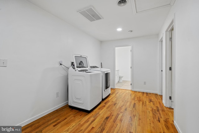 laundry area with washer and clothes dryer and light wood-type flooring