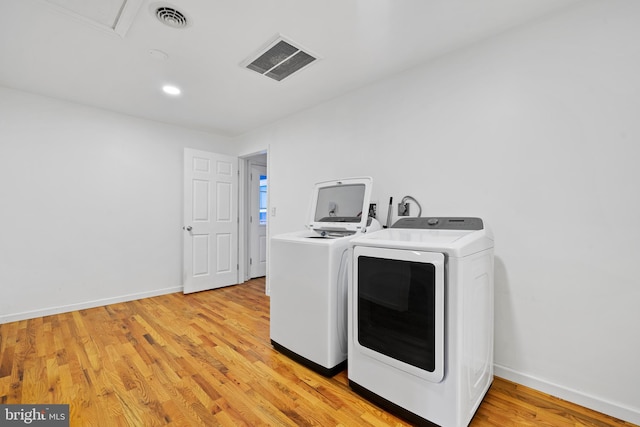 laundry room with washing machine and dryer and light wood-type flooring