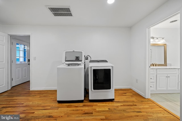 laundry room featuring washing machine and dryer and light wood-type flooring