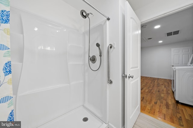 bathroom with wood-type flooring, a shower with curtain, and washer and clothes dryer