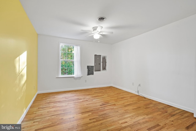 spare room featuring electric panel, ceiling fan, and light wood-type flooring