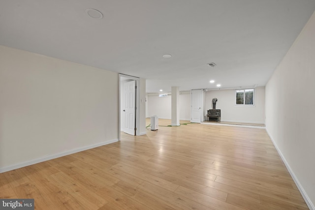 interior space with a wood stove and light hardwood / wood-style flooring