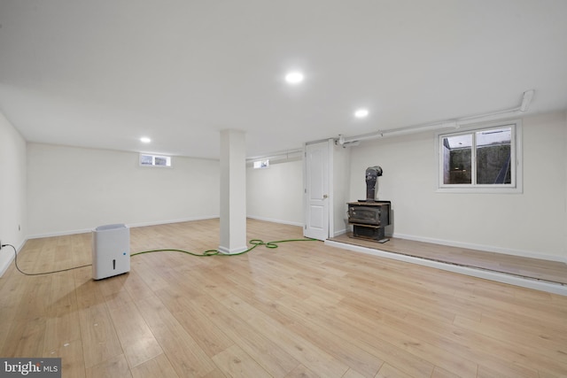 basement featuring a wood stove and light hardwood / wood-style floors