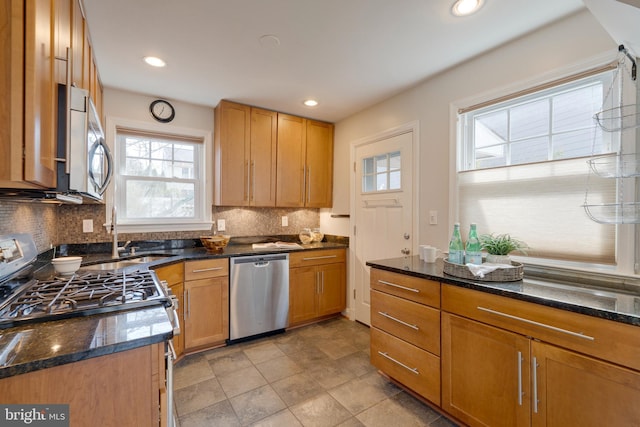 kitchen featuring appliances with stainless steel finishes, dark stone counters, backsplash, and recessed lighting