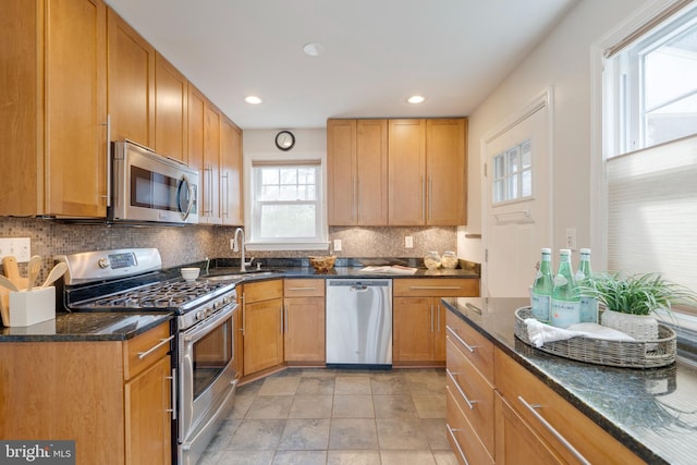 kitchen with recessed lighting, a sink, appliances with stainless steel finishes, dark stone counters, and tasteful backsplash